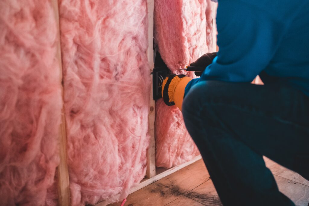 a photo of a person installing insulation used in the blog post for 8 Tips to Save Money on Energy Bills