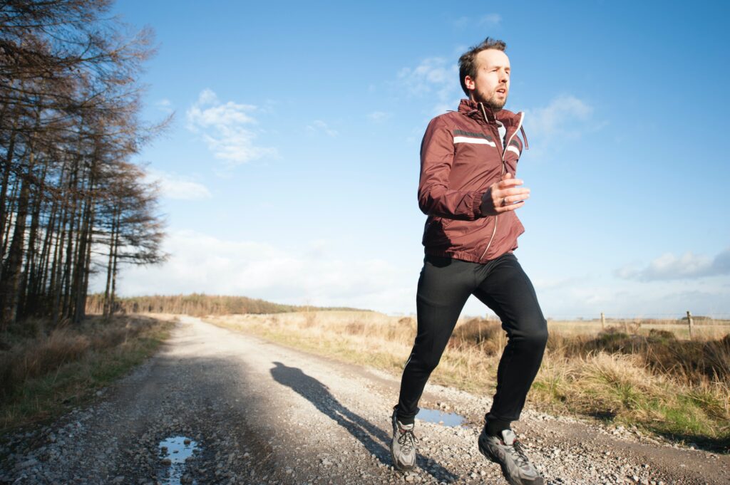 a person running on a dirt road, a photo being used for a blog to stay fit this winter